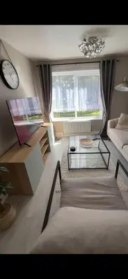 a living room with a couch and a table and a clock at DK House in Colchester