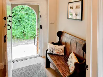 a room with a wooden bench and an open door at The Church Rooms in Wenhaston