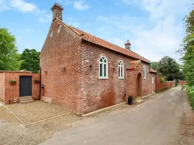 an old red brick church with a driveway at The Church Rooms in Wenhaston