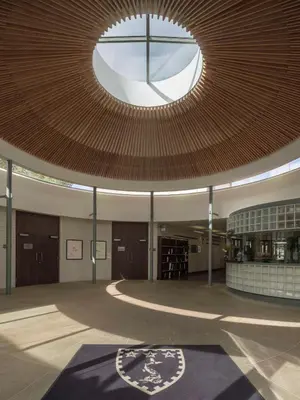 a large room with a large wooden ceiling with a window at Murray Edwards College, Cambridge in Cambridge