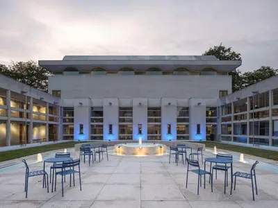 an exterior view of a building with tables and chairs at Murray Edwards College, Cambridge in Cambridge