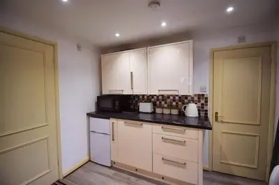 a kitchen with white cabinets and a black counter top at Mermaid Cottages in Frinton-on-Sea