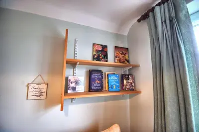 a book shelf with books on a wall at Mermaid Cottages in Frinton-on-Sea