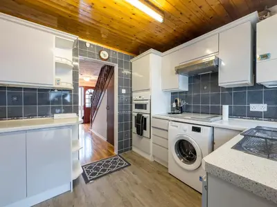 a kitchen with white cabinets and a washer and dryer at Cousy Haven in Laindon