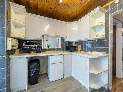 a kitchen with white cabinets and a wooden ceiling at Cousy Haven in Laindon