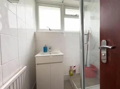 a white bathroom with a sink and a shower at Cousy Haven in Laindon