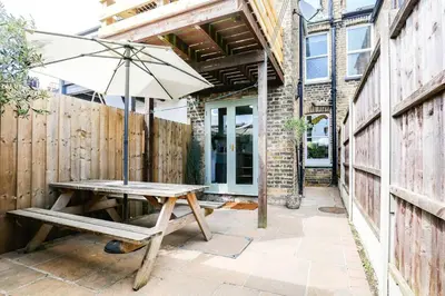 a wooden table with an umbrella and a bench at Stunning Cottage in the Heart of Old Leigh - Pass the Keys in Southend-on-Sea