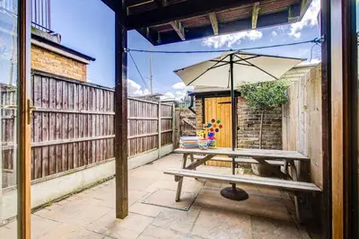 a picnic table with an umbrella on a patio at Stunning Cottage in the Heart of Old Leigh - Pass the Keys in Southend-on-Sea