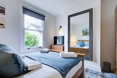 a bedroom with a bed and a large mirror at Stunning Cottage in the Heart of Old Leigh - Pass the Keys in Southend-on-Sea