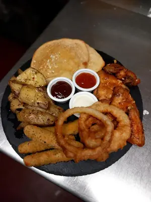 a plate of food with onion rings and a sandwich at The Chequers in Downham Market