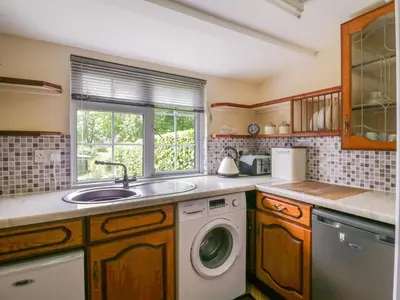 a kitchen with a sink and a washing machine at The Cottage in Sudbury
