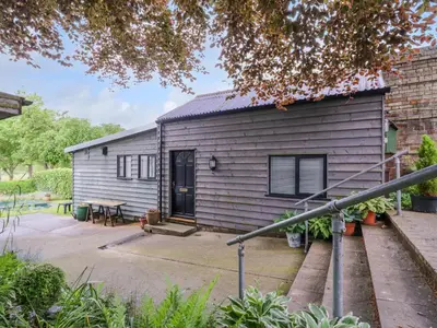 a gray house with a patio and a table at The Cottage in Sudbury