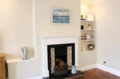 a living room with a fireplace with a picture on the wall at Cosy Cottage in Mersea - Walking distance to beach and town in West Mersea