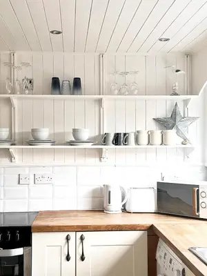 a kitchen with white cabinets and a counter top at Cosy Cottage in Mersea - Walking distance to beach and town in West Mersea