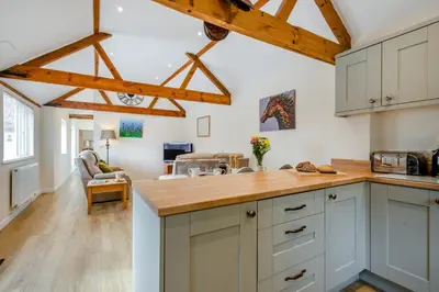 a kitchen with white cabinets and wooden beams at The Old Dairy & The Old Stables in Thetford