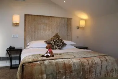 a teddy bear sitting on a bed in a hotel room at Bedford Lodge Hotel & Spa in Newmarket