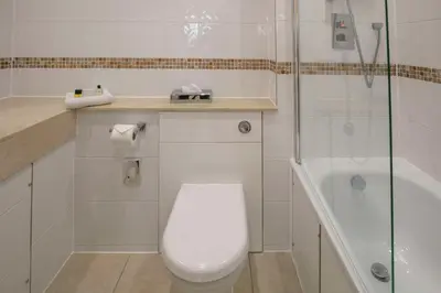 a white bathroom with a toilet and a shower at Best Western Heath Court Hotel in Newmarket