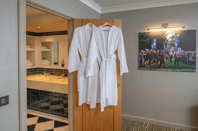 a white robe hanging on a door in a bathroom at Best Western Heath Court Hotel in Newmarket