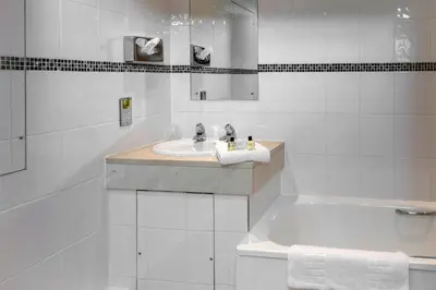 a white bathroom with a sink and a tub at Best Western Heath Court Hotel in Newmarket