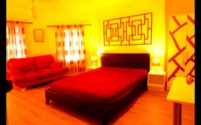 a bedroom with a red bed and a red couch at Cambridge city centre accommodations in Cambridge
