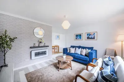 a living room with a blue couch and a fireplace at Kingside Residence Stevenage in Stevenage
