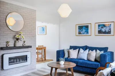 a living room with a blue couch and a fireplace at Kingside Residence Stevenage in Stevenage