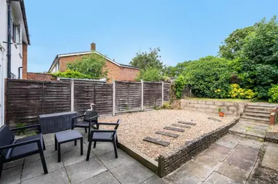 a garden with chairs and a table and a fence at Kingside Residence Stevenage in Stevenage