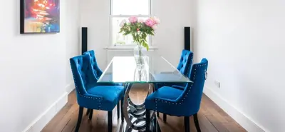 a dining room table with blue chairs and a vase of flowers at Stunning sea views from rooms and terraces in Leigh-on-Sea