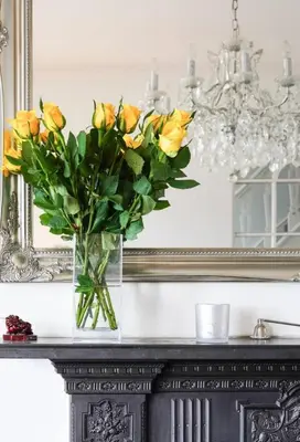 a vase of yellow roses on a table in front of a mirror at Stunning sea views from rooms and terraces in Leigh-on-Sea