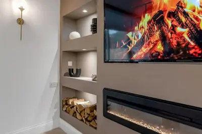 a living room with a tv above a fireplace at The old Stables in Wymondham