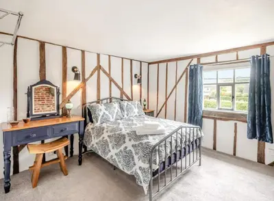 a bedroom with a bed and a desk and a window at Meadowland Holiday Cottage in Eye
