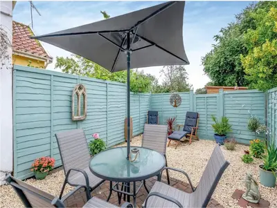 a patio with a table and chairs and an umbrella at Meadowland Holiday Cottage in Eye