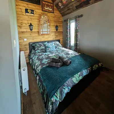 a bedroom with a bed in a wooden cabin at Lake View lodges The Lavenham in Long Melford