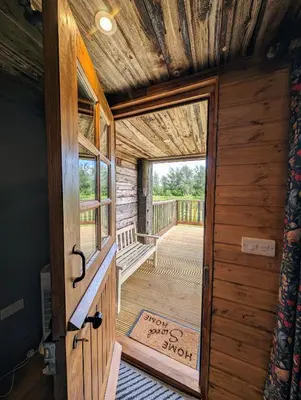 an open door to a porch in a log cabin at Lake View lodges The Lavenham in Long Melford