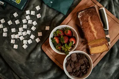 a wooden cutting board with two bowls of fruit and a plate of bread at Honeywood Farm Cabins in Woodham Ferrers