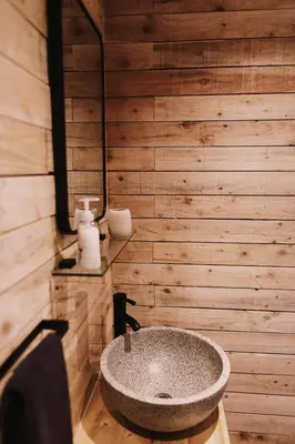 a bathroom with a stone sink on a wooden wall at Honeywood Farm Cabins in Woodham Ferrers