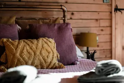 a bed with purple pillows on top of it at Honeywood Farm Cabins in Woodham Ferrers
