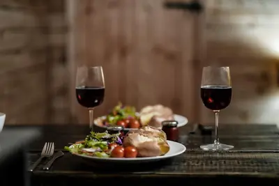 two glasses of red wine next to plates of food at Honeywood Farm Cabins in Woodham Ferrers