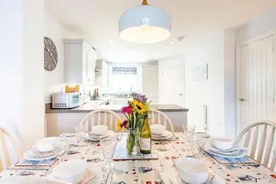 a dining room table with a vase of flowers on it at The Salty Dog, Aldeburgh in Aldeburgh