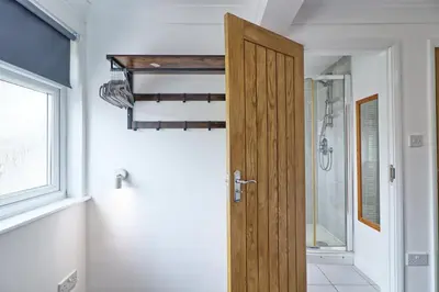 a bathroom with a wooden door and a shower at LMV Property - Modern Luxury Family Home in Theydon Bois With London Skyline Views in Theydon Bois