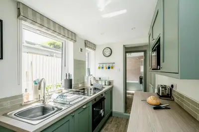 a kitchen with green cabinets and a sink and a window at Wigeon Cottage, Aldeburgh - Sleeps 4 - Adults only house in Aldeburgh