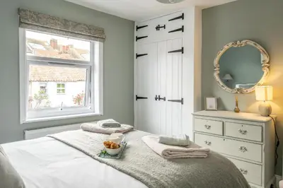 a bedroom with a bed with towels and a mirror at Wigeon Cottage, Aldeburgh - Sleeps 4 - Adults only house in Aldeburgh