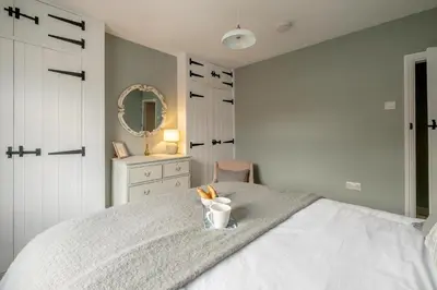 a bedroom with a bed with a cup and a mirror at Wigeon Cottage, Aldeburgh - Sleeps 4 - Adults only house in Aldeburgh