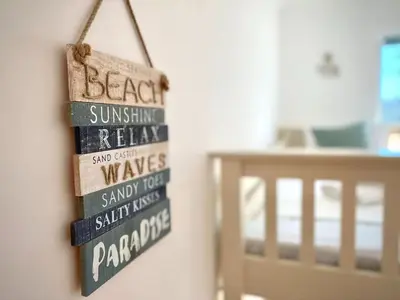 a sign hanging on a wall next to a bed at 2 Bedroom Apartment with Garden, Close to Beach in Southend-on-Sea