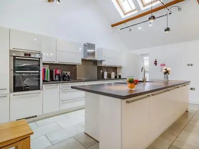 a kitchen with white cabinets and a black counter top at Barrow Barn in Wicken