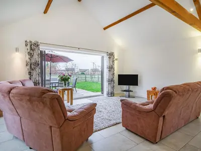 a living room with two chairs and a sliding glass door at Barrow Barn in Wicken