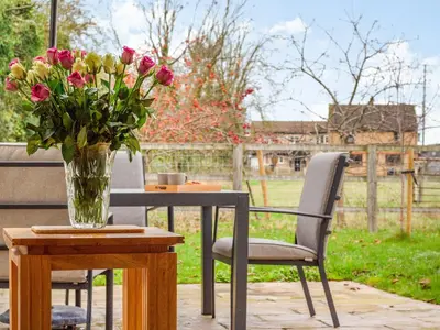 a vase of flowers on a table with a vase of roses at Barrow Barn in Wicken