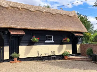 a house with a table and chairs in front of it at Lake House Cottage in Finchingfield