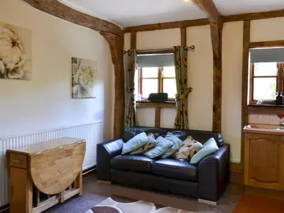 a living room with a black leather couch at Lake House Cottage in Finchingfield