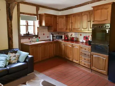 a kitchen with wooden cabinets and a black leather couch at Lake House Cottage in Finchingfield